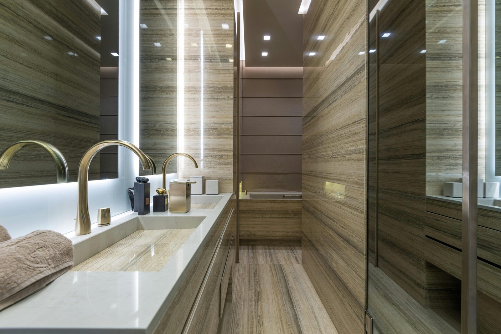 Elegant modern bathroom with marble surfaces and gold fixtures, featuring minimalistic design.
